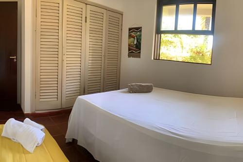 a bedroom with a large white bed and a window at Casa das Palmeiras (Pé na Areia) - Maré Verde in Rio das Ostras