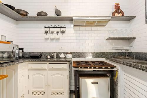 a kitchen with white cabinets and a stove top oven at Casa das Palmeiras (Pé na Areia) - Maré Verde in Rio das Ostras