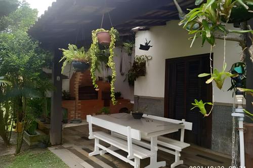 a white picnic table in front of a house with plants at Casa das Palmeiras (Pé na Areia) - Maré Verde in Rio das Ostras