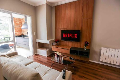 a living room with a couch and a tv at Condessa 115 - Funcional e completo a poucos passos do Capivari in Campos do Jordão
