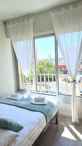un lit dans une chambre avec une grande fenêtre dans l'établissement Lyly Home, au Cap d'Agde