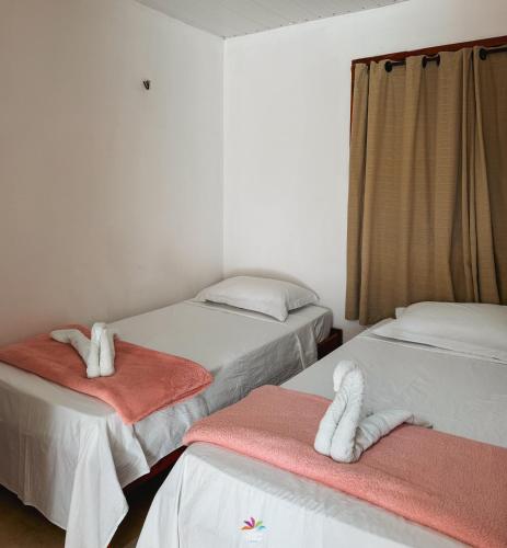 a room with two beds with towels on them at Pousada Curva dos Ventos in Icaraí