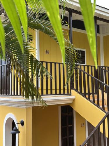 a yellow house with a balcony and palm leaves at El Oasis Hotel in Aguada