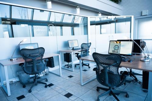 an office with three desks with chairs and two monitors at Hotel Blackfoot in Calgary
