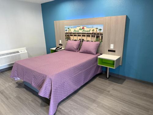 a bedroom with a large bed with purple sheets at Hi-Way Host Motel in Pasadena