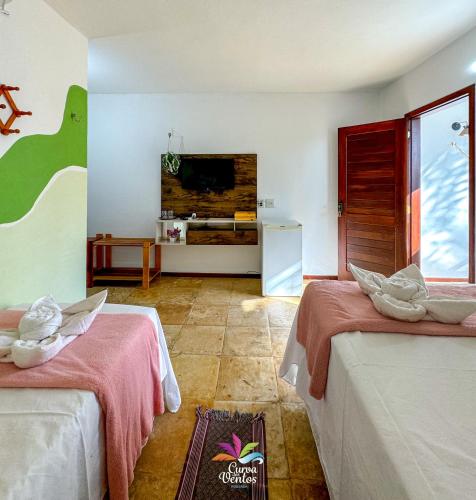 a hotel room with two beds and a television at Pousada Curva dos Ventos in Icaraí