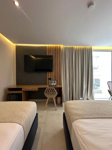 a hotel room with two beds and a desk with a television at Hotel y Cabañas Covemar in Coveñas