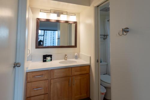 a bathroom with a sink and a mirror at Spacious & Affordable Waikiki Getaway - Perfect for Families & Groups, Near Beach includes Free Parking (22208) in Honolulu