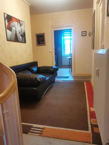 a living room with a black leather couch and a blue door at Ferienwohnung in einem alten Bauernhaus in Lontzen