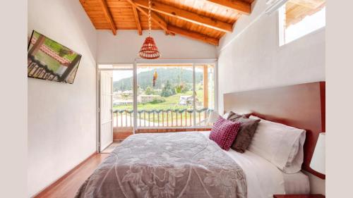 a bedroom with a bed and a large window at HOTEL BOUTIQUE 14 LANCEROS in Paipa