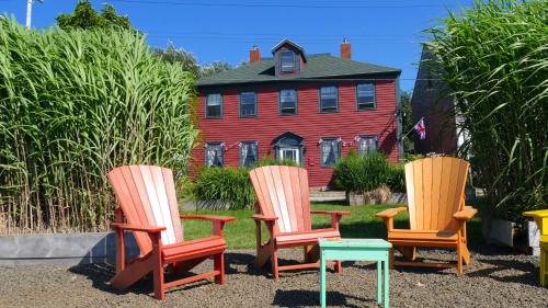 three chairs and a table in front of a house at Bailey House Bed and Breakfast in Annapolis Royal