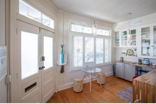 a kitchen with white walls and windows and a table at Romantic Studio Apt in Historic Downtown Savannah in Savannah