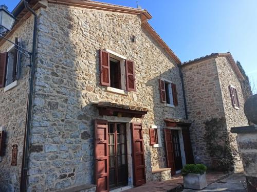 un vecchio edificio in pietra con persiane rosse di GiuMa Tuscany Historic Lux Farmhouse near Saturnia Spa a Montemerano