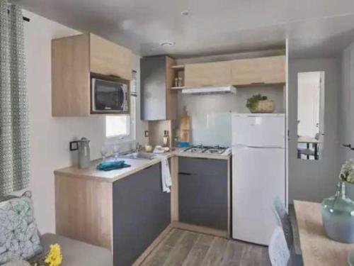 Elle comprend une petite cuisine équipée d'un réfrigérateur blanc et d'un évier. dans l'établissement Camping 4 étoiles - Piscine - eed0eh, à Thégra