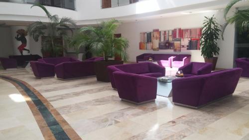 a lobby with purple couches and potted plants at Hotel Atrium Plaza in Barranquilla