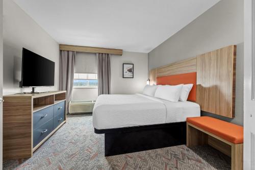 a hotel room with a bed and a flat screen tv at Candlewood Suites Flowood, MS by IHG in Luckney