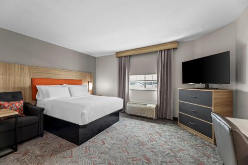 a hotel room with a bed and a flat screen tv at Candlewood Suites Flowood, MS by IHG in Luckney