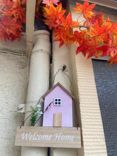 a welcome home sign on a building with autumn leaves at Mini Bungalow in Mainz
