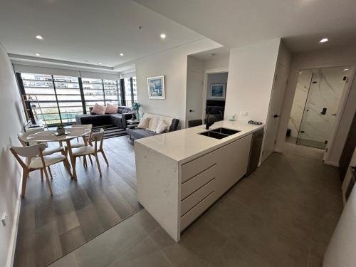 a kitchen and living room with a table and a couch at Modern coastal living with 5G & Netflix in Wollongong