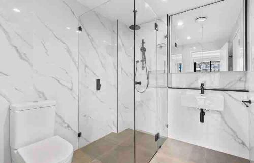 a white bathroom with a shower and a toilet at Modern coastal living with 5G & Netflix in Wollongong