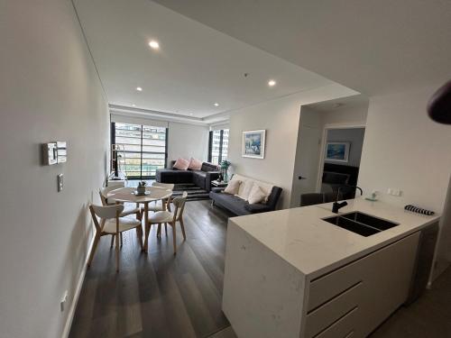a kitchen and living room with a table and a couch at Modern coastal living with 5G & Netflix in Wollongong