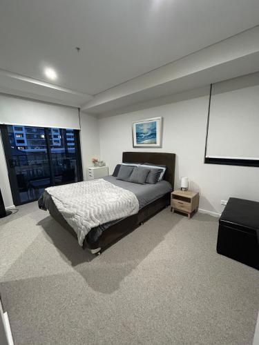 a bedroom with a large bed and a large window at Modern coastal living with 5G & Netflix in Wollongong