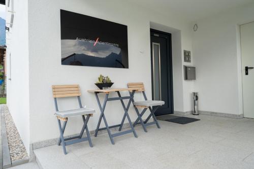two chairs and a table with a tv on a wall at Austrian Apartments in Bad Goisern