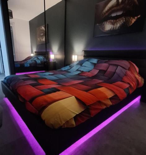 une chambre avec un lit coloré avec des lumières dessus dans l'établissement T2 Cosy romantic, balcon,clim, parking gratuit, à Perpignan