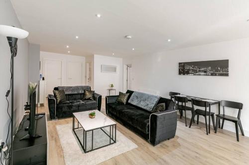 a living room with a black couch and a table at New Modern and Spacious 2BR In The Heart of Burnley with Free Private Parking in Burnley