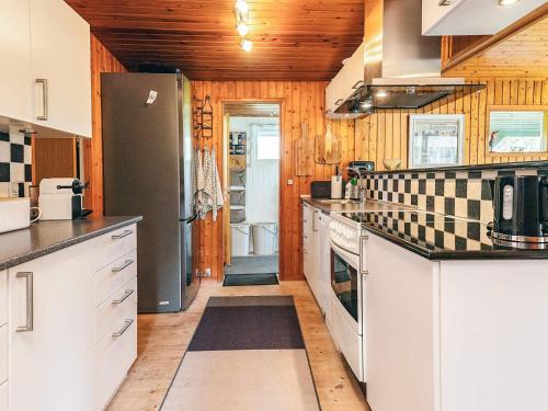 a kitchen with white cabinets and a black refrigerator at 6 person holiday home in Dannemare in Dannemare