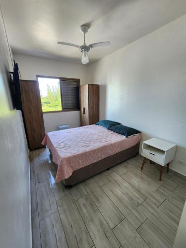a bedroom with a bed and a ceiling fan at Apartamento Peruíbe in Peruíbe