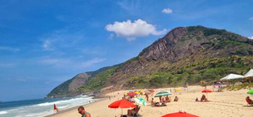 a group of people on a beach with umbrellas at Apto Térreo Recreio Praia 9 min a pé com Ar Cond in Rio de Janeiro