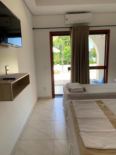 a room with two beds and a sink and a window at Pousada Santa Fé in Aparecida