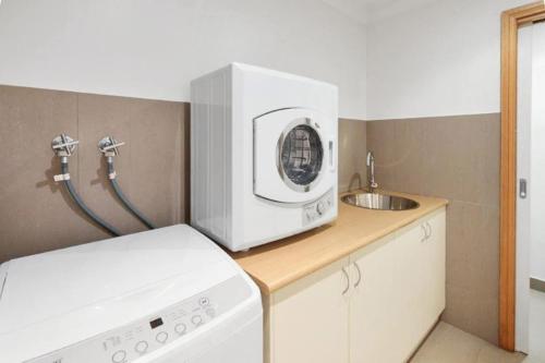 a kitchen with a washing machine and a sink at 5 Connelly - Echuca Holiday Homes in Echuca