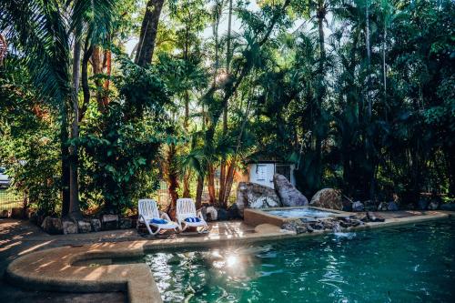 a swimming pool with two chairs and a fountain at BIG4 Howard Springs Holiday Park in Darwin