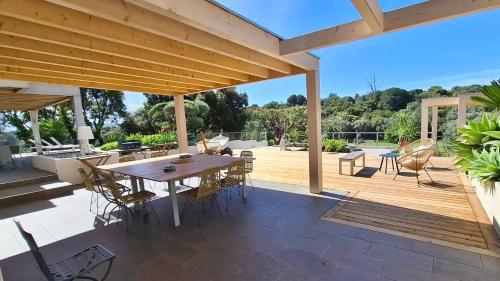 une terrasse en bois avec une table et des chaises en bois dans l'établissement VillaSerenita Piscine chauffée et SPA à Ajaccio, à Ajaccio