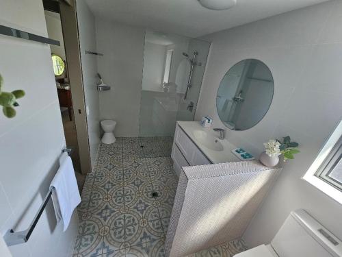 a white bathroom with a sink and a mirror at The Waterford Prestige Apartments in Caloundra