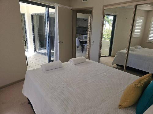 a bedroom with a large white bed and a view of a room at The Waterford Prestige Apartments in Caloundra