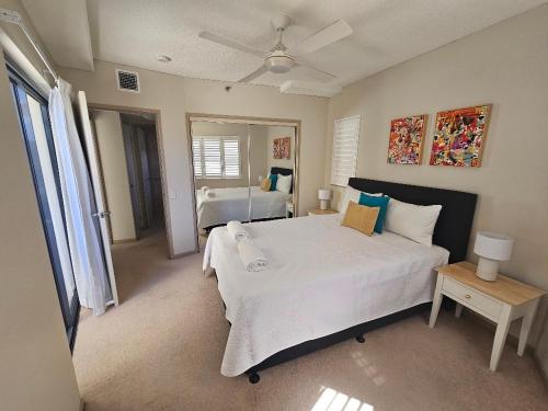 a bedroom with a large white bed and a mirror at The Waterford Prestige Apartments in Caloundra
