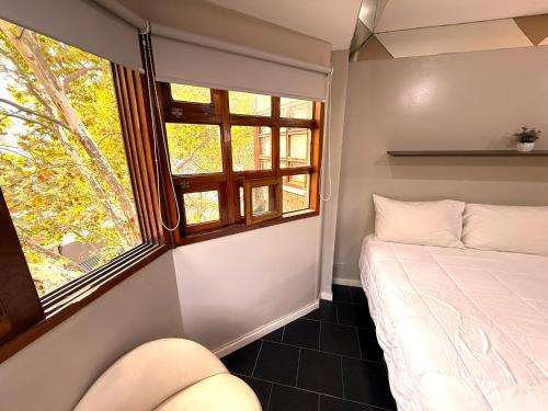 a person laying on a bed in a room with a window at Casa Recoleta - Hoteles Recoleta in Buenos Aires