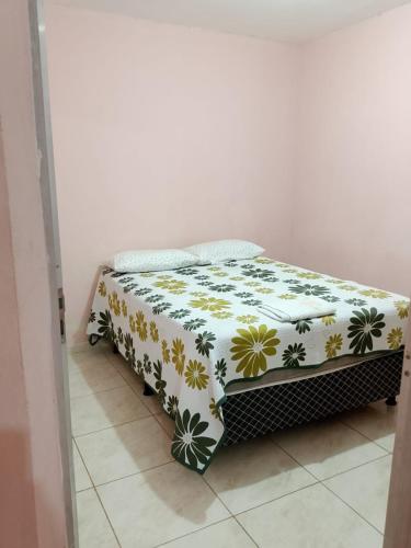 a bed in a room with a floral blanket on it at Casa Aconchegante de 2 quartos e 2 camas de casal in Juazeiro do Norte