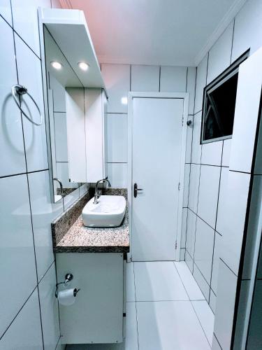 a white bathroom with a sink and a mirror at Cobertura em Caiobá-Matinhos-Pr 2 quadras do mar in Matinhos