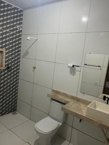 a white bathroom with a toilet and a sink at Casa Ampla com 5 camas e 2 quartos in Juazeiro do Norte