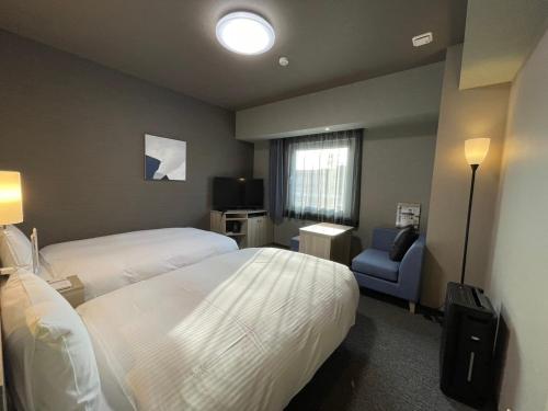 a hotel room with two beds and a blue chair at Hotel Route Inn Okayama Ibara in Ibara