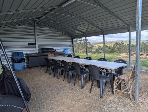 a table and chairs in a tent with a grill at Big Tree Farmhouse in Rathdowney