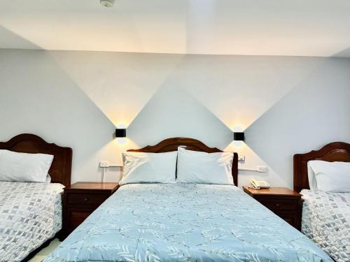 a bedroom with two beds and two lamps at Hotel Tiwintza Internacional in Quito