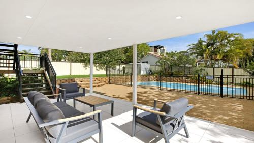 a patio with chairs and a swimming pool at Sunset On View - Picturesque Coastal Setting With Pool in The Entrance