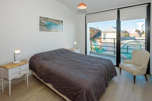 a bedroom with a bed and a chair and a balcony at Mioceno in Puerto Madryn