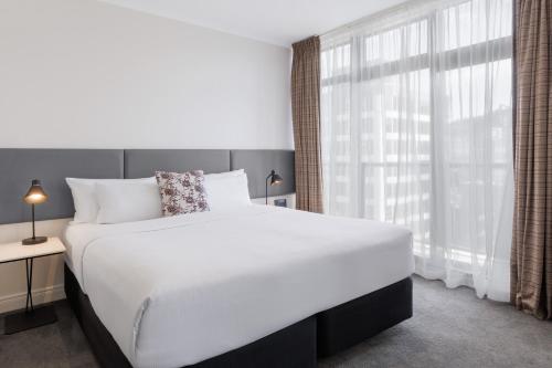 a bedroom with a large bed and a large window at Adina Citylife Auckland in Auckland