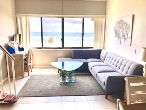 a living room with a blue couch and a table at Oceanview Condo with Loft & AC in Kaaawa